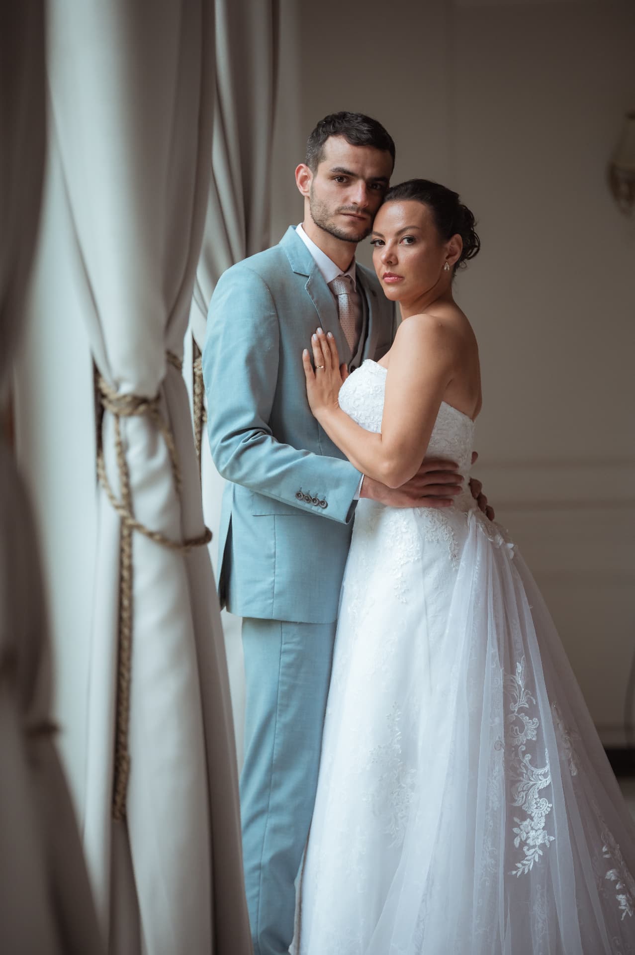 Caroline e Quentin abraçados junto às cortinas