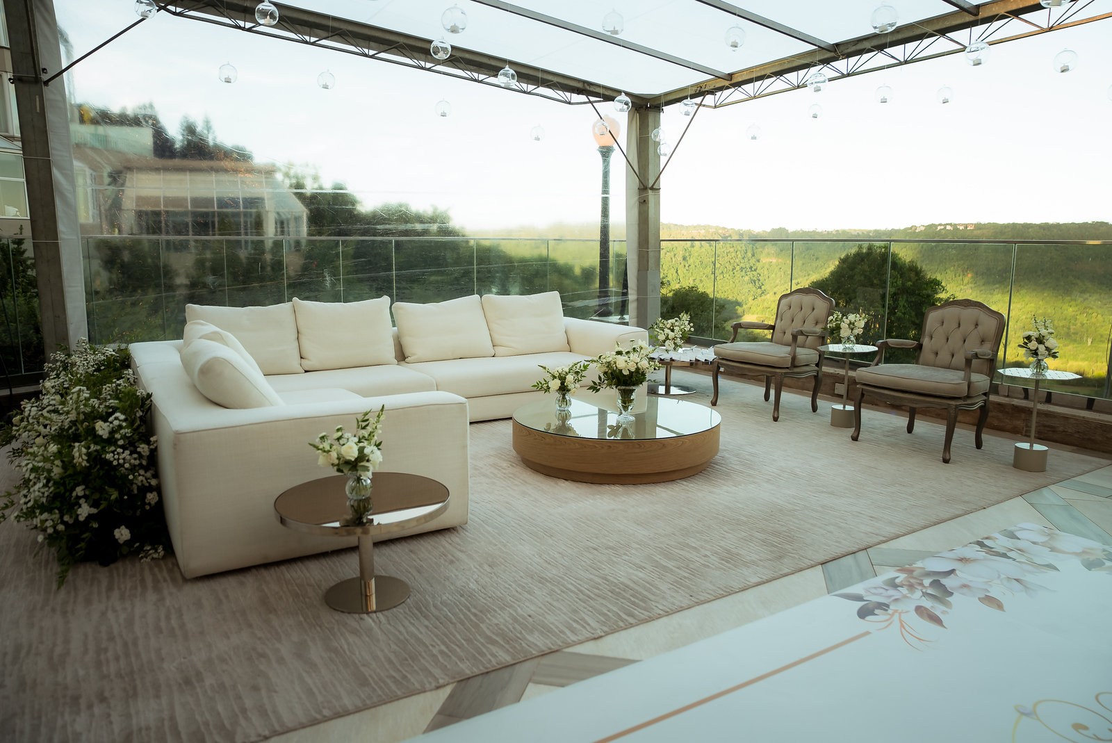 Lounge com sofá branco e vista para a mata