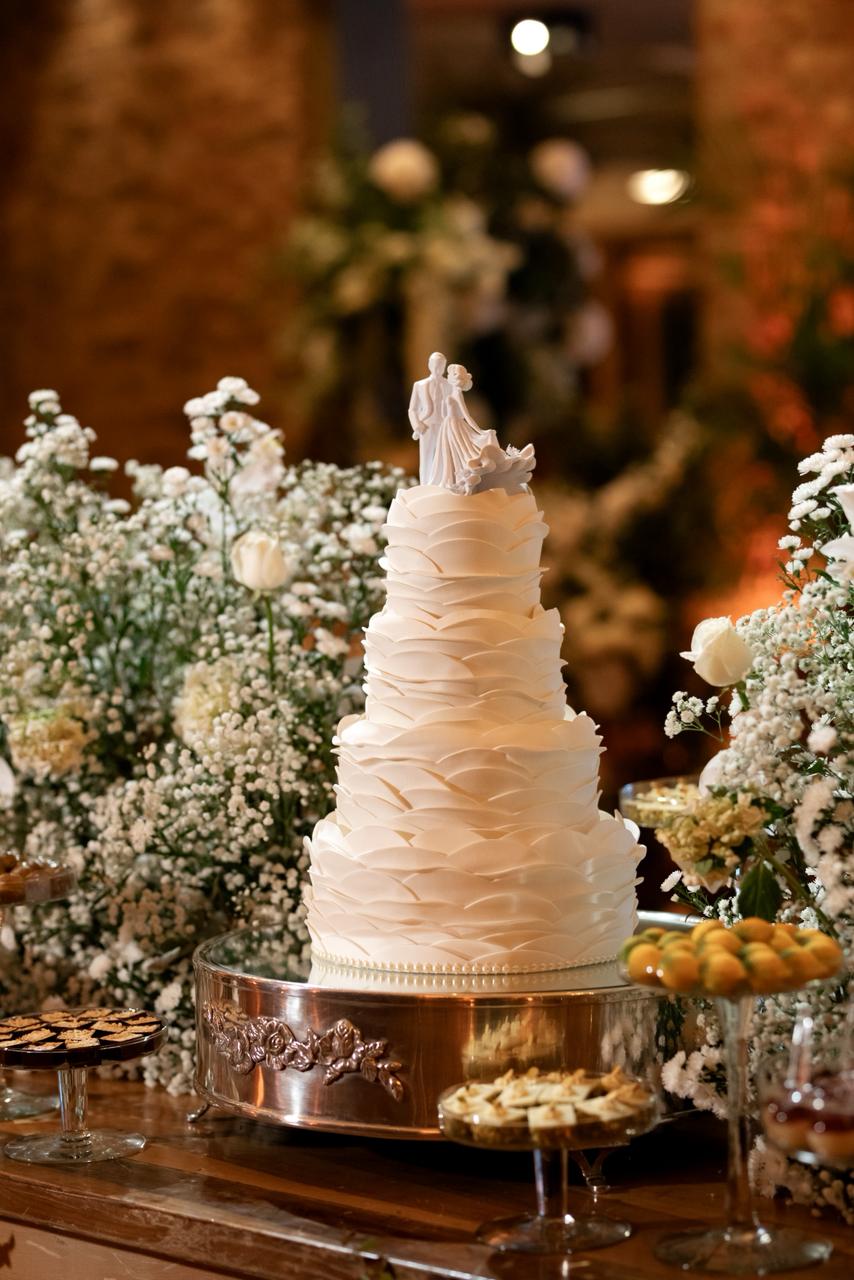 Bolo de casamento cercado de flores brancas